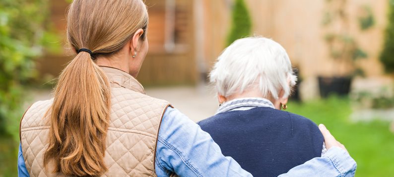 young woman walking away with arm around elderly woman's shoulders
