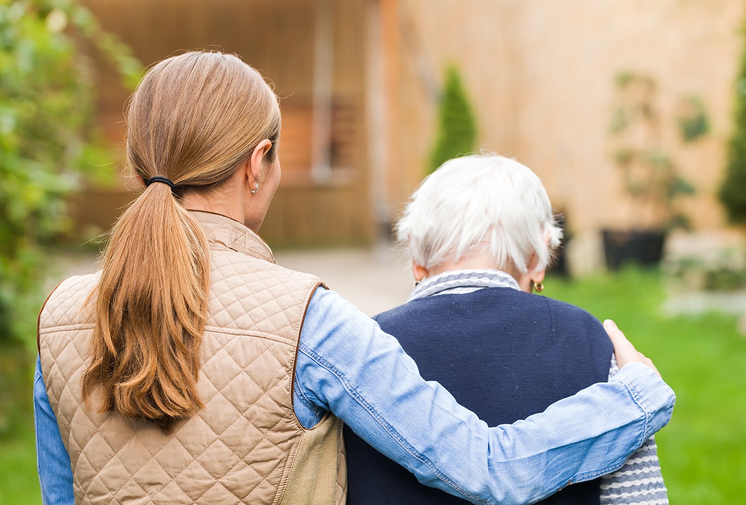 young woman walking away with arm around elderly woman's shoulders