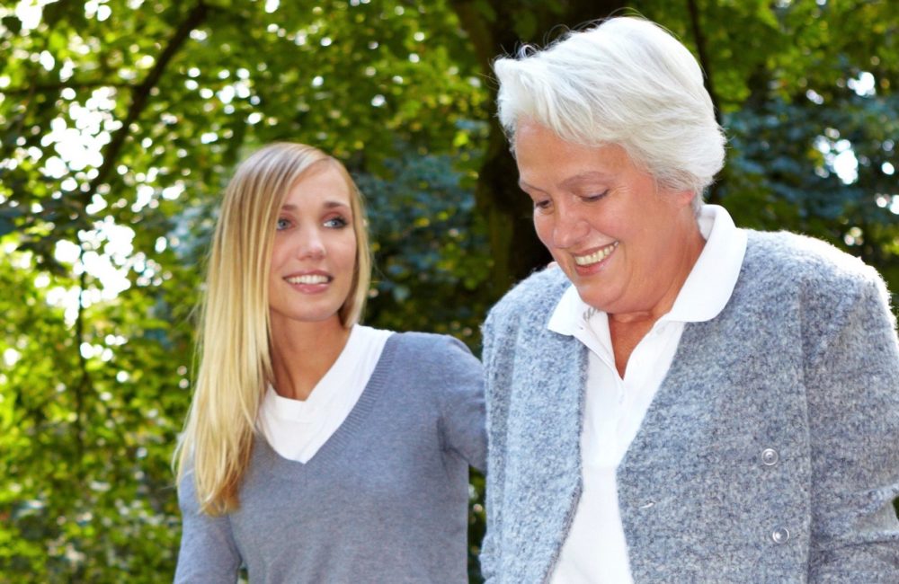 Elderly mother walking outside with adult daughter