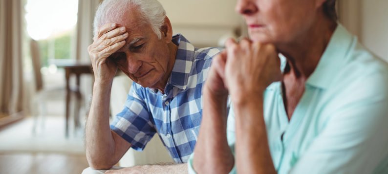 Upset senior couple sitting on sofa