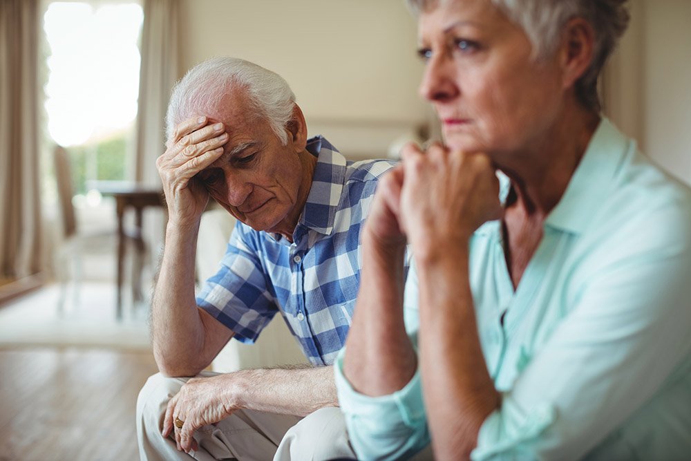 Upset senior couple sitting on sofa