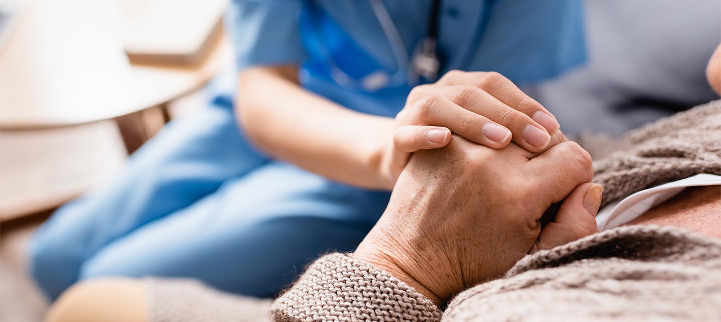 Nurse holding older person's hand.