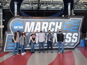 Research team in from of March Madness sign all wearing masks