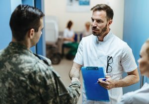 Doctor and military man shaking hands while standing in a lobby at the hospital.