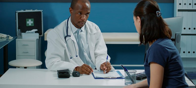physician taking notes while talking with a patient