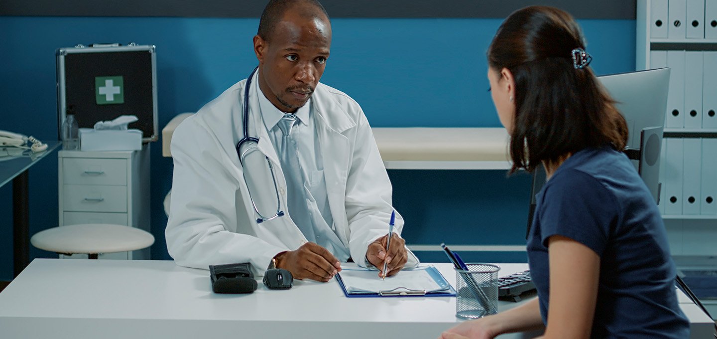 physician taking notes while talking with a patient