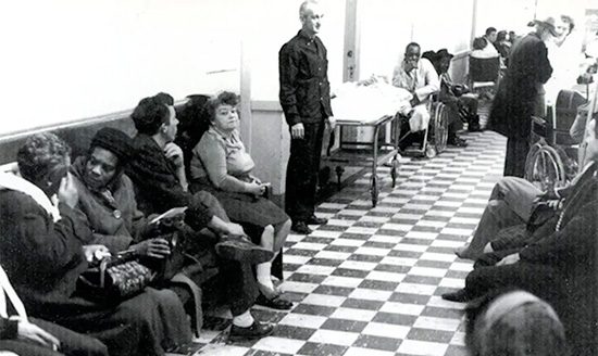 vintage black and white photo of people waiting in line at county safety net hospital